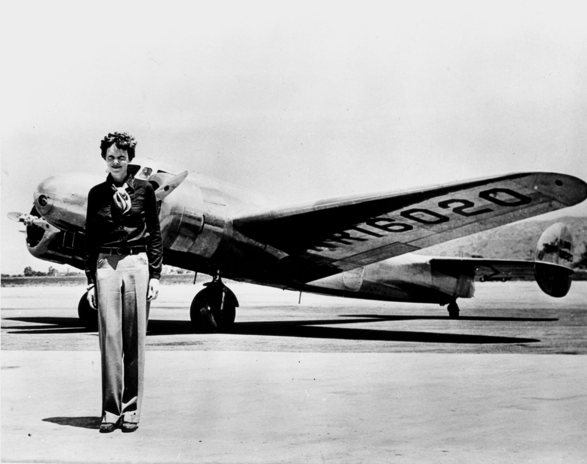 Amelia Earhart. W tle jej samolot z ostatniego, fatalnego lotu