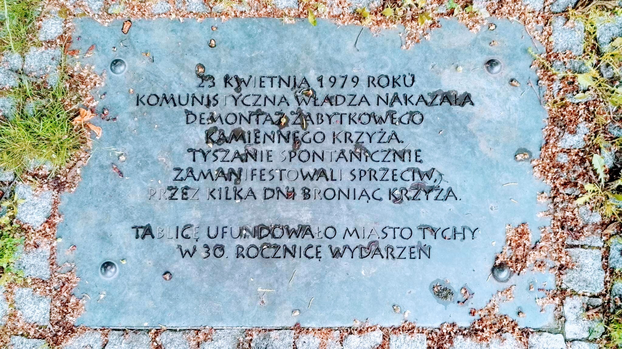 Pamiątkowa tablica przy kamiennym krzyżu w Tychach
